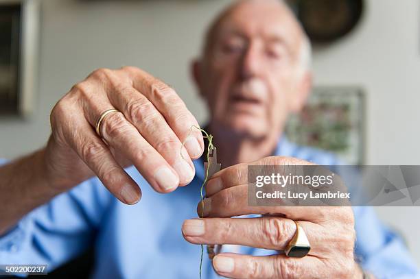 senior man threading his embroidery needle - mani fili foto e immagini stock