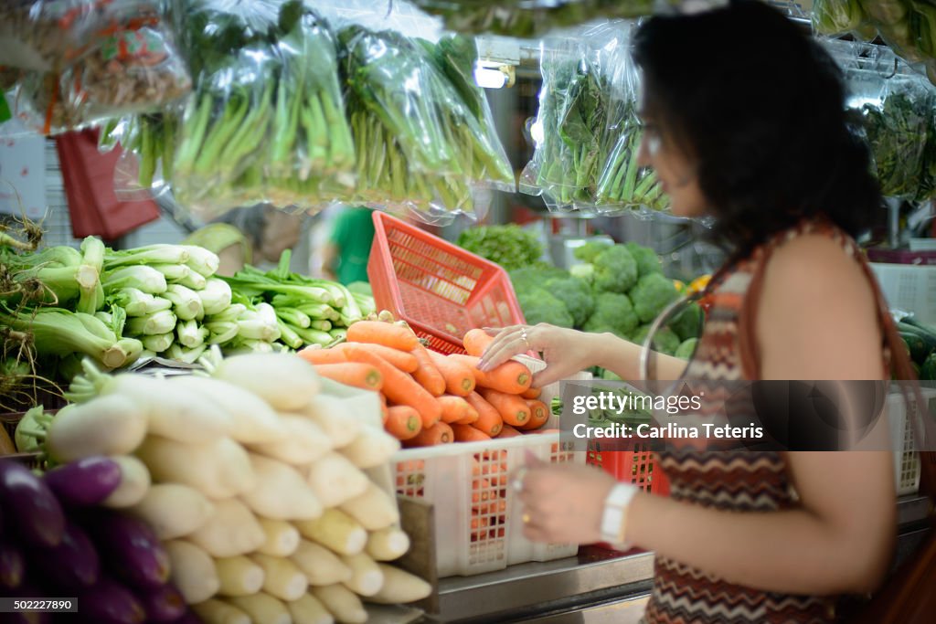 Woman shops for vegetables at wet market
