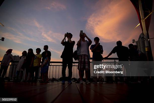 Visitors take photographs at Asiatique The Riverfront open-air mall at dusk in Bangkok, Thailand, on Friday, Dec. 18, 2015. Thai economic indicators...