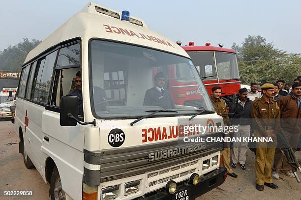 Members of the Delhi Police stand alongside an ambulance at the crash site of a chartered army plane close to the main airport in New Delhi on...