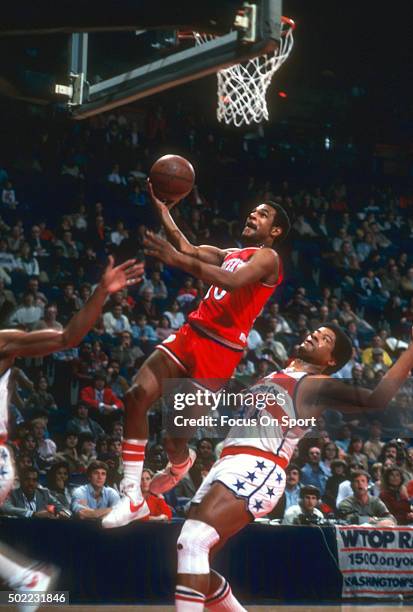 Maurice Cheeks of the Philadelphia 76ers lays the ball up in front of Wes Unseld of the Washington Bullets during an NBA basketball game circa 1979...