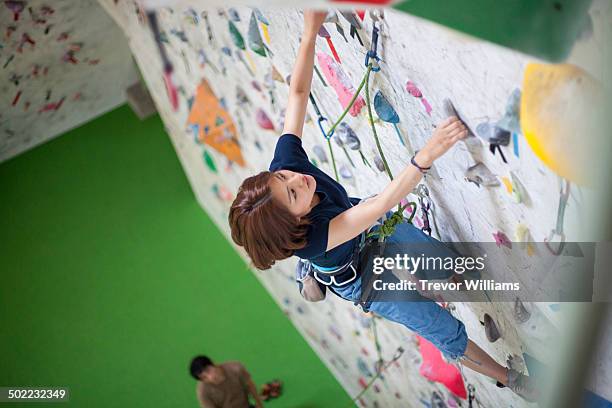 a young woman climbs a rock climbing wall - bouldering stock pictures, royalty-free photos & images