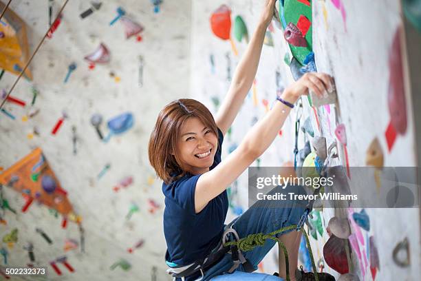 a young woman climbs at a rock climbing gym - boulderen stockfoto's en -beelden