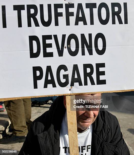 Participant holds a sign reading 'the fraudsters, they have to pay' during a protest against the collapse of four Italian banks in central Rome on...