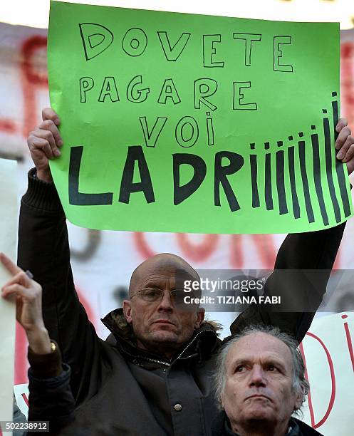 Participant holds up a placard reading 'thieves, you have to pay' during a protest against the collapse of four Italian banks in central Rome on...