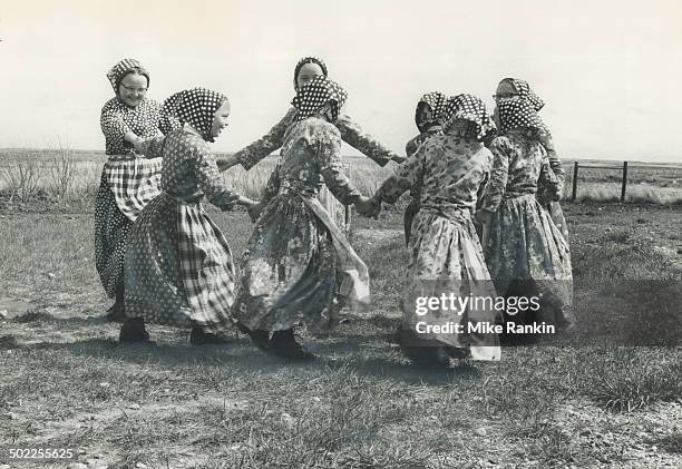 Hutterite girls in everyday dress dance in a circle during school recess in a Saskatchewan settlement