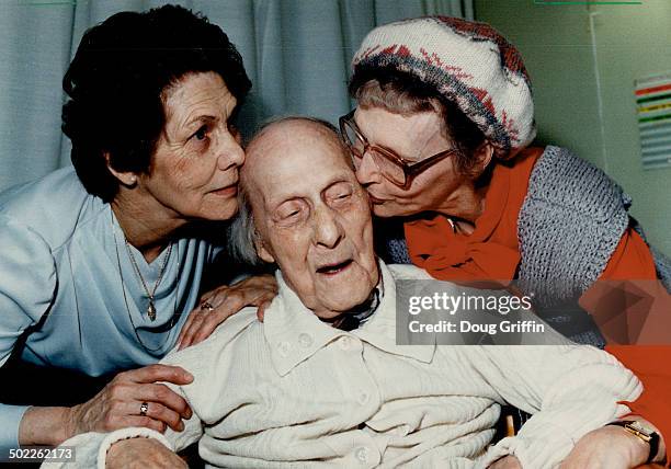 Happy birthday! Alfred Hughes; who turns 107 today; gets a kiss from his daughters; Florence Morrell and Jessie Hayhurst; in his wheelchair at...