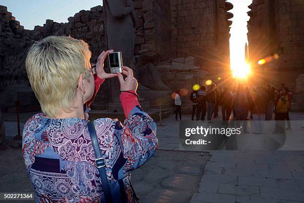 Tourist takes pictures as the sun rises behind the Temple of Karnak during the alignment of the winter solstice sunrise to the temple in the southern...