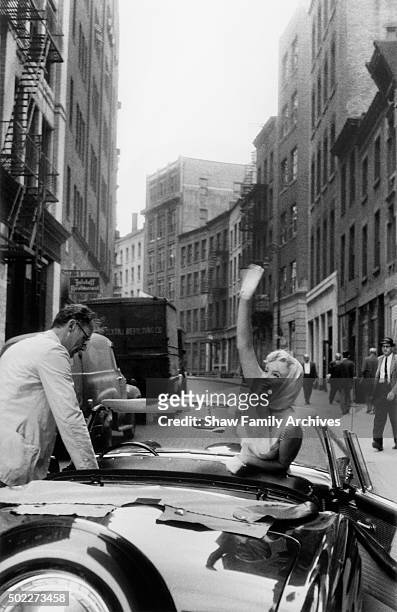 Marilyn Monroe waves from a convertible Ford Thunderbird with her husband and playwright Arthur Miller in 1957 in New York, New York.