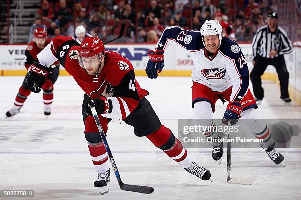 Stefan Elliott of the Arizona Coyotes skates ahead of David Clarkson of the Columbus Blue Jackets during the NHL game at Gila River Arena on December...