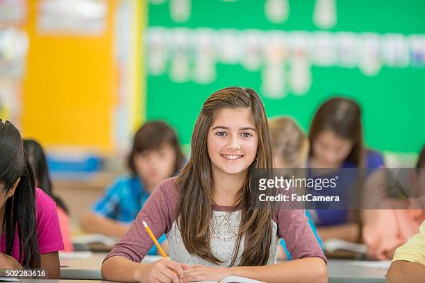 young girl happily sitting in class - 13 pencils stockfoto's en -beelden
