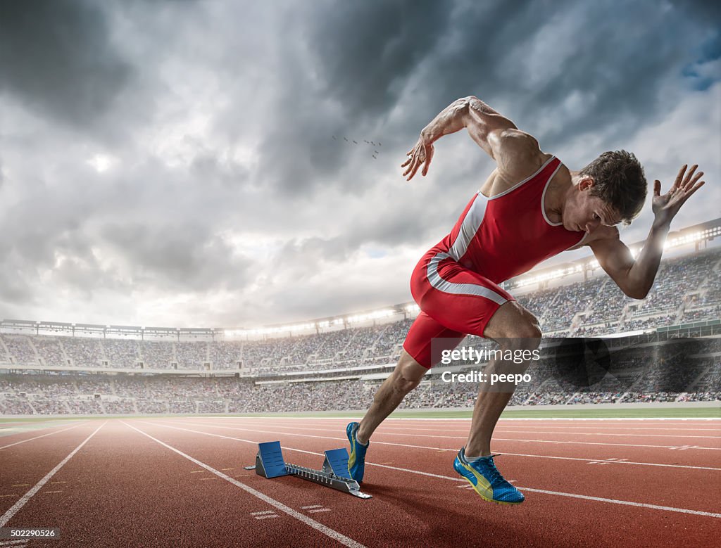 Elite 100m Runner Sprints From Blocks in Floodlit Stadium