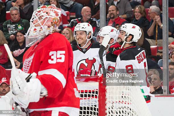 David Schlemko of the New Jersey Devils celebrates his first period goal with teammates Jiri Tlusty and Jon Merrill behind goaltender Jimmy Howard of...