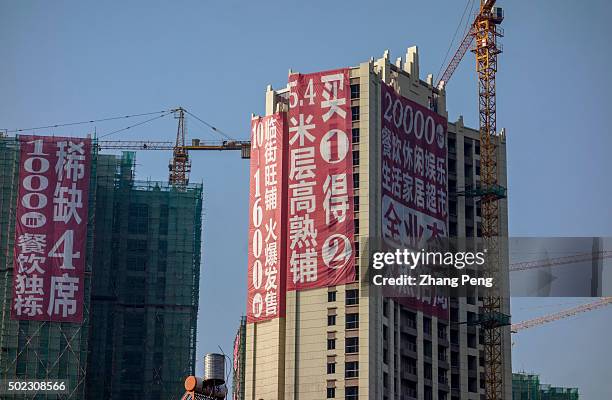 Huge promotion advertisement hangs on a real estate project under construction. The ratio of supply to demand in Kunming is 2.39 and the new house...