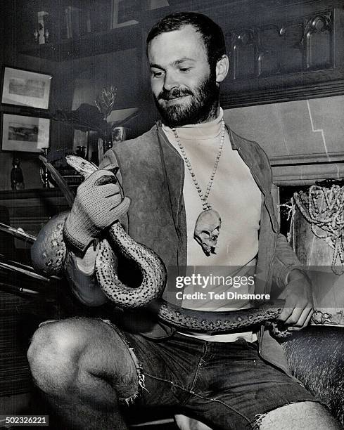 Norman Elder holds 7-FT. Anaconda he brought from Peru. Around his neck is a monkey skull on a necklace of beads.