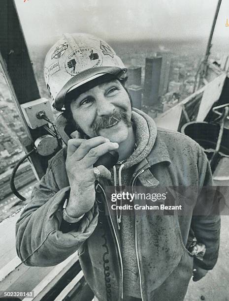 On top of things as he talks to the crane operator is Bill Eustace; the ironworkers' signalman on the afternoon shift of the CN Tower which when...