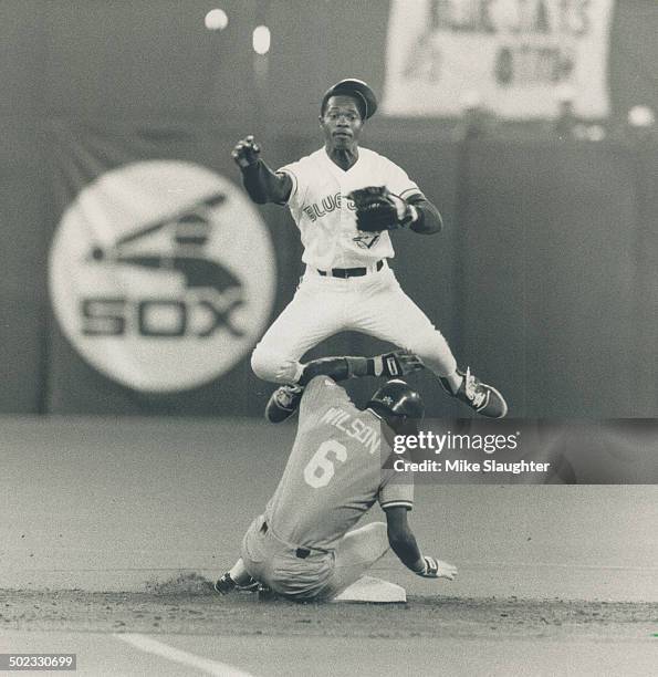 Double trouble: Blue Jays shortstop Tony Fernandez leaps to avoid a sliding Kansas City Royals baserunner Willie Wilson and complete a double play...