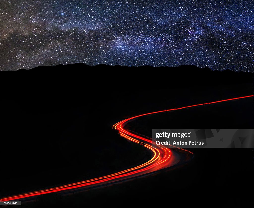 Brightly lit road at night along the mountain