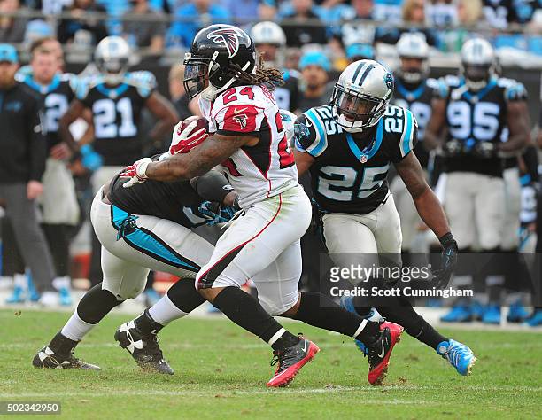 Devonta Freeman of the Atlanta Falcons carries the ball against Bene Benwikere of the Carolina Panthers at Bank Of America Stadium on December 13,...