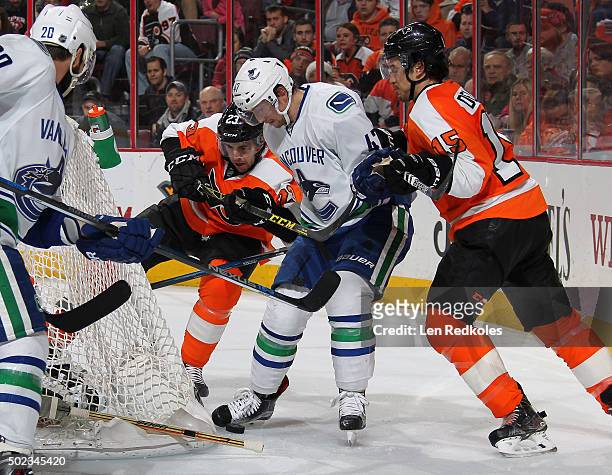 Brandon Manning and Michael Del Zotto of the Philadelphia Flyers battle for the puck behind the net against Sven Baertschi and Chris Higgins of the...