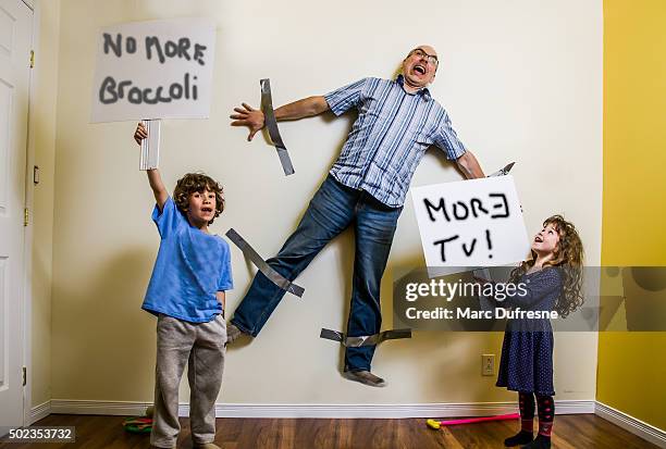 kinder-rebellion hat zu umgurtung geschmückt, die der vater an der wand - family with two children stock-fotos und bilder