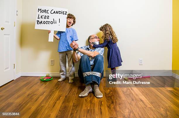 two kids having their father as hostage with duct tape - anti bullying stockfoto's en -beelden