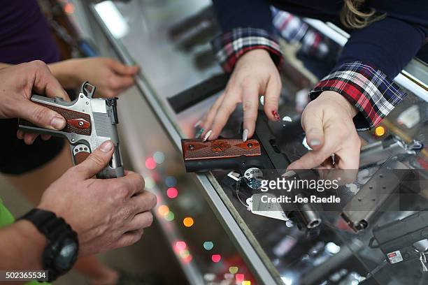 Customer compares handguns before buying one as a Christmas present at the National Armory gun store on December 23, 2015 in Pompano Beach, Florida....