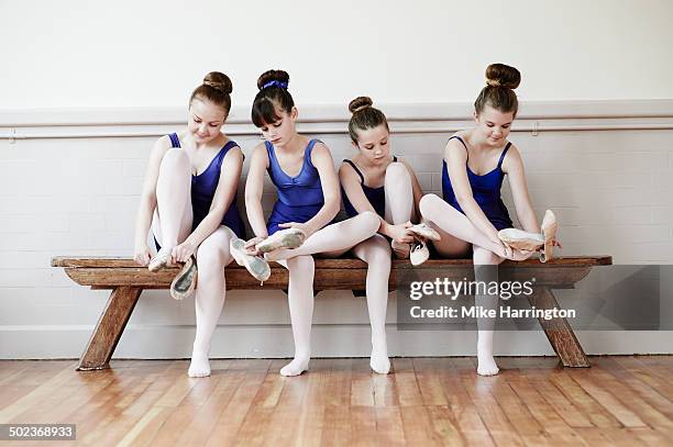 four ballet dancers putting on ballet shoes - dancing classrooms stock pictures, royalty-free photos & images