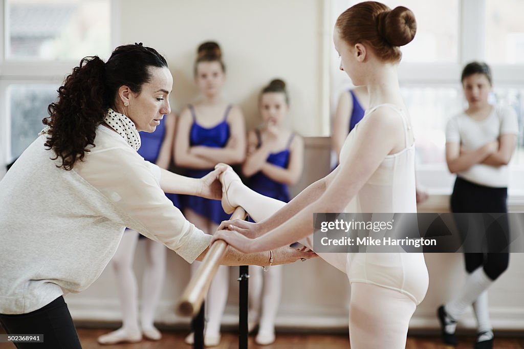 Ballet teacher helping dancer in dance studio