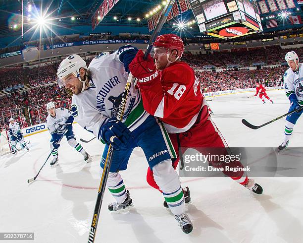 Chris Tanev of the Vancouver Canucks battles in the corner with Joakim Andersson of the Detroit Red Wings during an NHL game at Joe Louis Arena on...