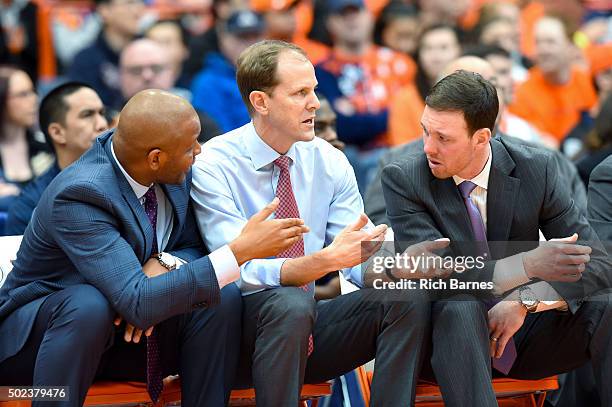 Assistant coach Adrian Autry and assistant coach Gerry McNamara talk with acting head coach Mike Hopkins of the Syracuse Orange on the bench against...