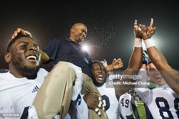 Interim head coach Dell McGee of the Georgia Southern Eagles gets lifted into the air by defensive end Ryan George and defensive end Nardo Govan of...