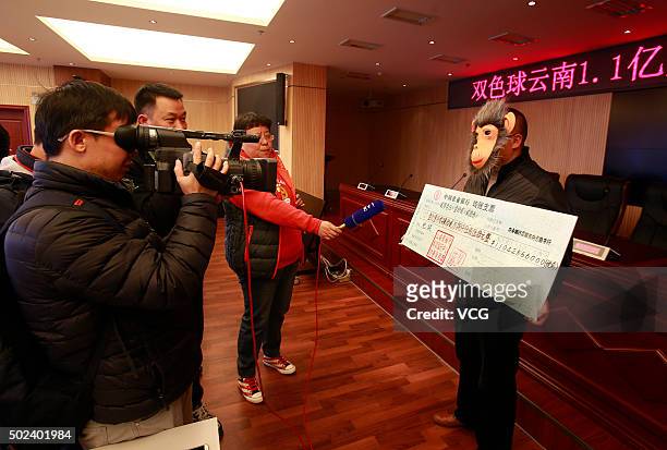 The man wearing a monkey mask poses with a cheque of over 110 million RMB lottery winnings at Yunnan welfare lotteries distribution center on...