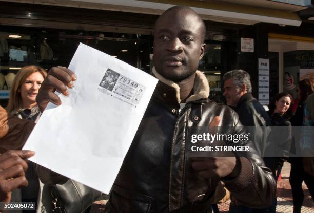 Senegalese Ngame thumbs up as he holds a photocopy of a winning lottery ticket of the Spanish Christmas' lottery draw on December 22, 2015 in the...