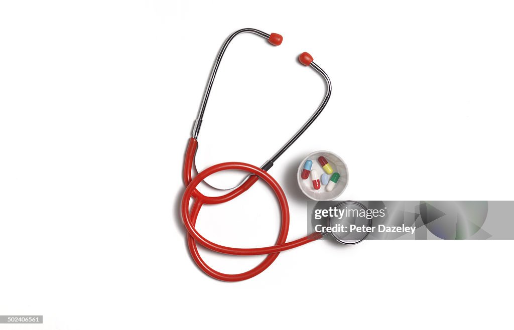 Red stethoscope with pills and copy space
