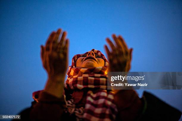 Kashmiri Muslim woman looks towards a cleric displaying the holy relic believed to be the hair from the beard of the Prophet Mohammed at Hazratbal...