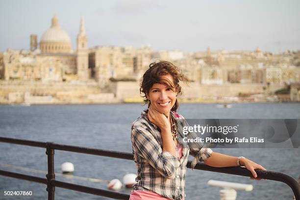 pretty smiling woman leaning against handrail by the sea in valletta (malta) - la valletta foto e immagini stock