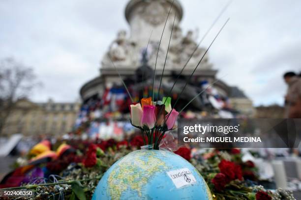 This picture taken on December 24, 2015 shows a globe and roses on a makeshift memorial at Place de la Republique in Paris on December 24, 2015 to...