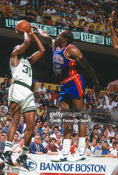 Reggie Lewis of the Boston Celtics shoots over Vinnie Johnson of the Detroit Pistons during an NBA basketball game circa 1991 at the Boston Garden in...
