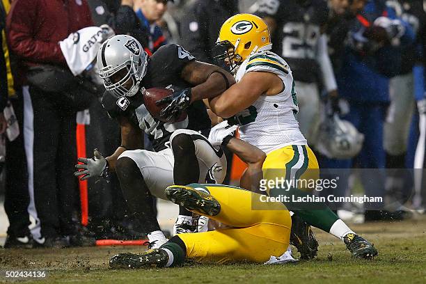 Full back Marcel Reece of the Oakland Raiders is tackled by line backers Joe Thomas and Nick Perry of the Green Bay Packers in the fourth quarter at...