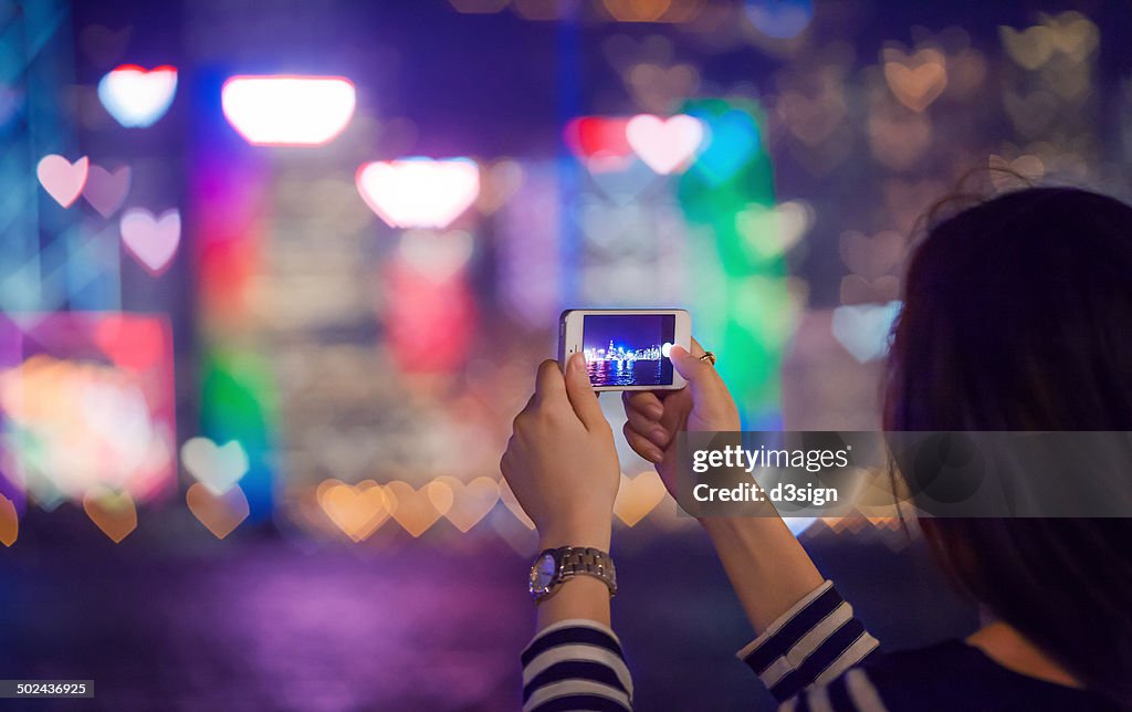 Asian female taking picture of blurry heart bokeh