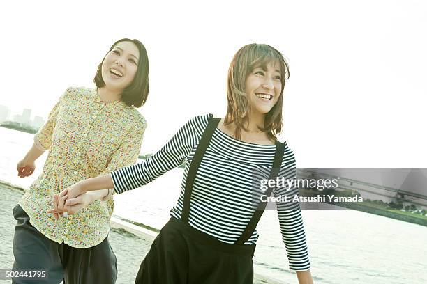 young japanese women running on beach,smiling - women in suspenders 個照片及圖片檔