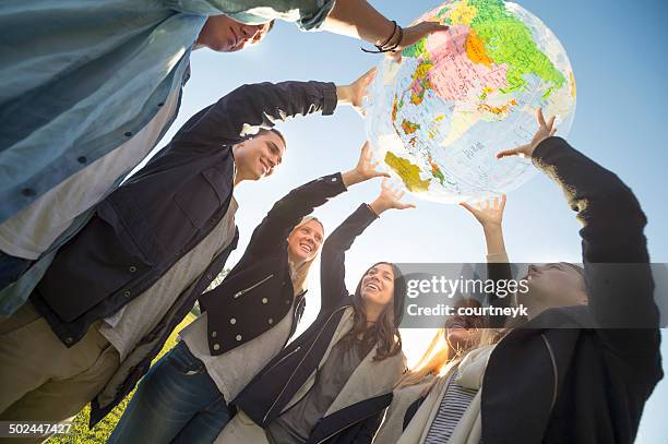 group of people holding a world globe - migration people stockfoto's en -beelden