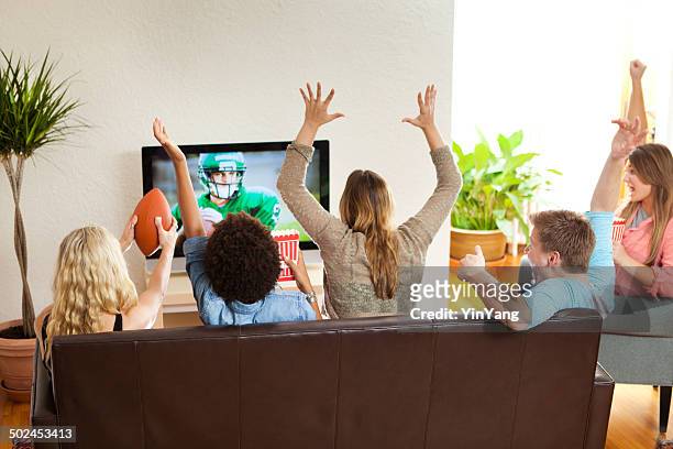 group of friends watching and cheering football game together - watching stock pictures, royalty-free photos & images