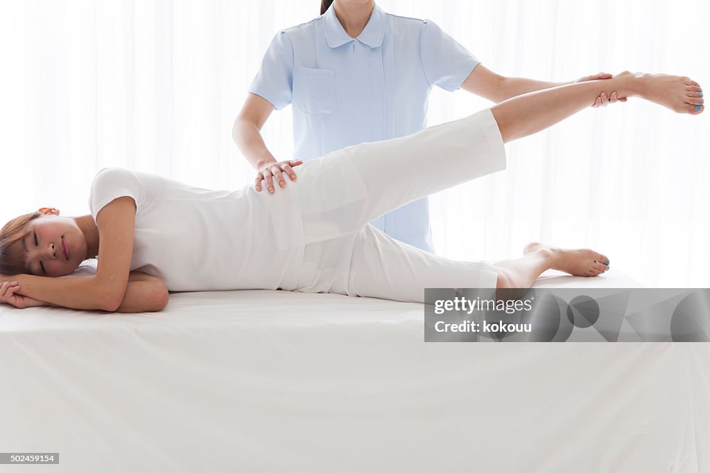 Physiotherapist massaging leg of young woman at spa
