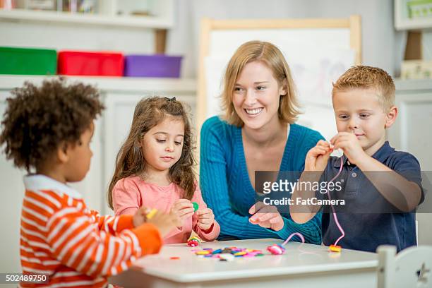 children stringing beads together - bead string stock pictures, royalty-free photos & images