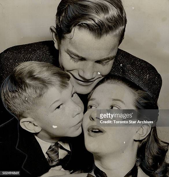 Member of the Canadian Army show; Lois Maxwell; being kissed by brother David; seven; as Keith looks on; stayed in London when the army show broke up...