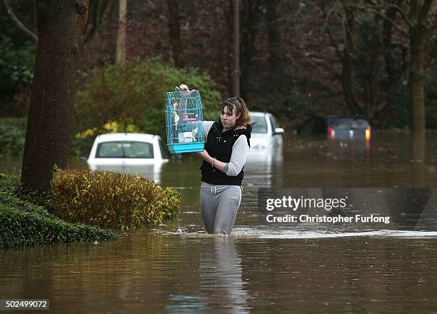 Woman carries a birdcage as she wades through floodwater after the River Calder burst its bank's in the Calder Valley town of Mytholmroyd on December...