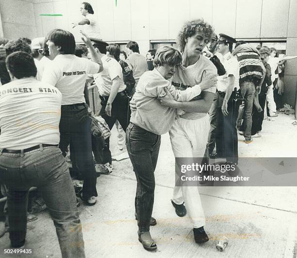 Helping hands: Two would-be ticket-buyers help each other away from the scene after crowds pushed forward in a line-up to buy tickets to Bruce...