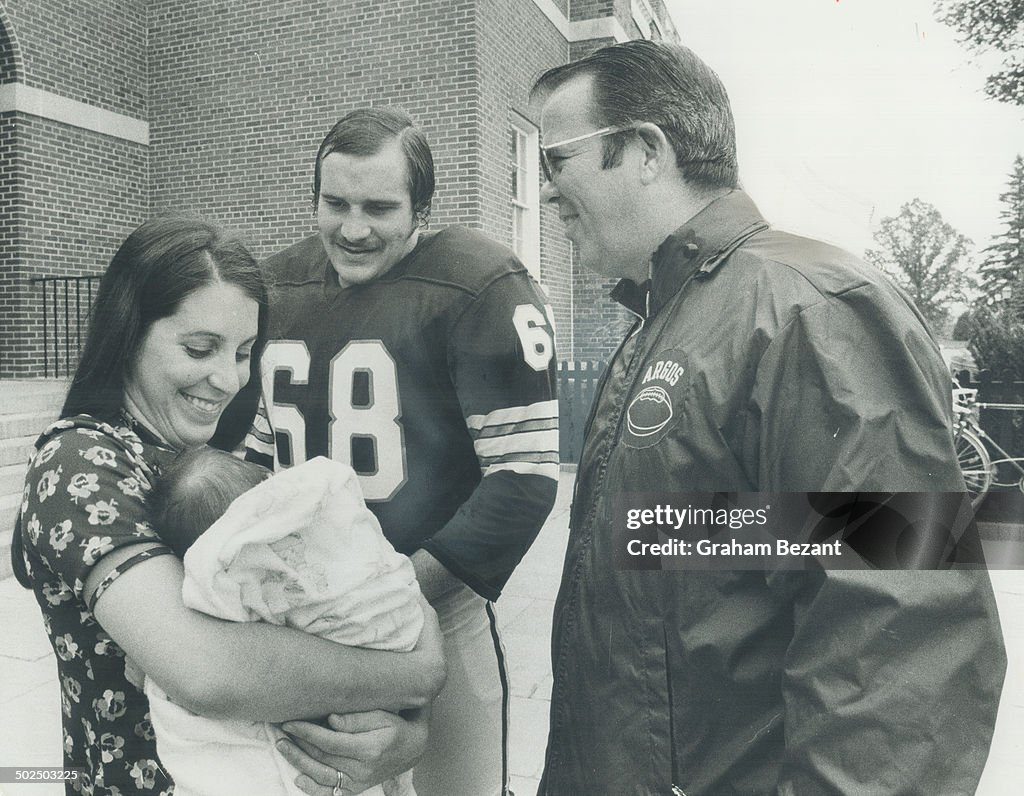 All in the family: Head coach Leo Cahill (right) admires new addition to Jim Stillwagon's family; 3-